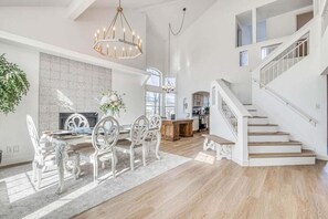A spacious living area with a dining table, chairs, a chandelier, and a staircase. - Villa de Montana: Breathtaking Sunset Views (El Paso)