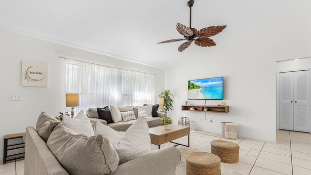 Un salon moderne avec un canapé beige, une table basse et un ventilateur de plafond.