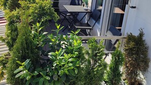A balcony with a table and chairs, surrounded by potted plants and a white fence. - Studio Apartment 'B + E Röck' with Private Balcony and Wi-Fi (Meckenbeuren)