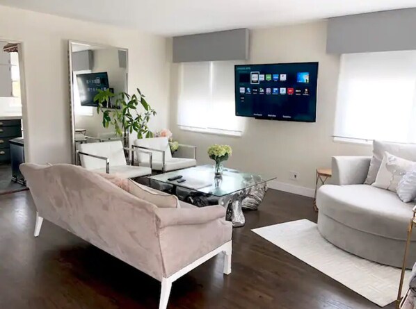 A modern living room with a sofa, coffee table, and a flat-screen TV mounted on the wall.