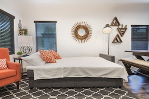 Relax in this serene bedroom with a large bed, floor lamp, and unique wall decor featuring potted plants.