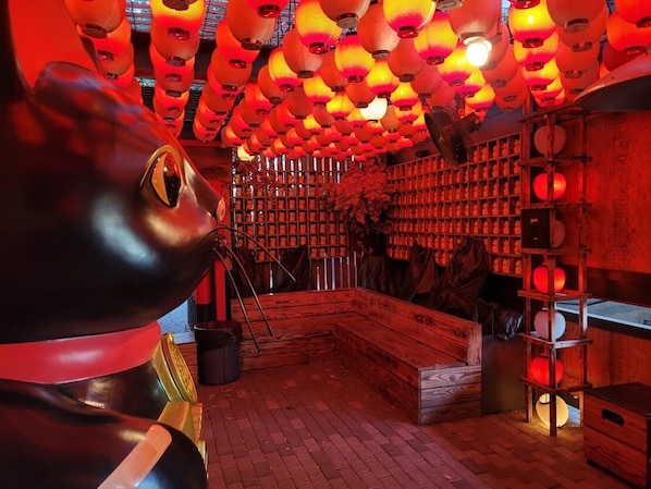 A room with a wooden bench, shelves with bottles, and a large fish sculpture.