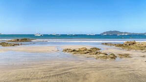 A beach with boats in the water and rocky areas in the foreground. - Quiet Tamarindo 2BR | 10-min Walk to the Beach! (Tamarindo)