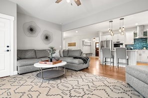 Un salon moderne avec un canapé gris, une table basse et un tapis à motifs.