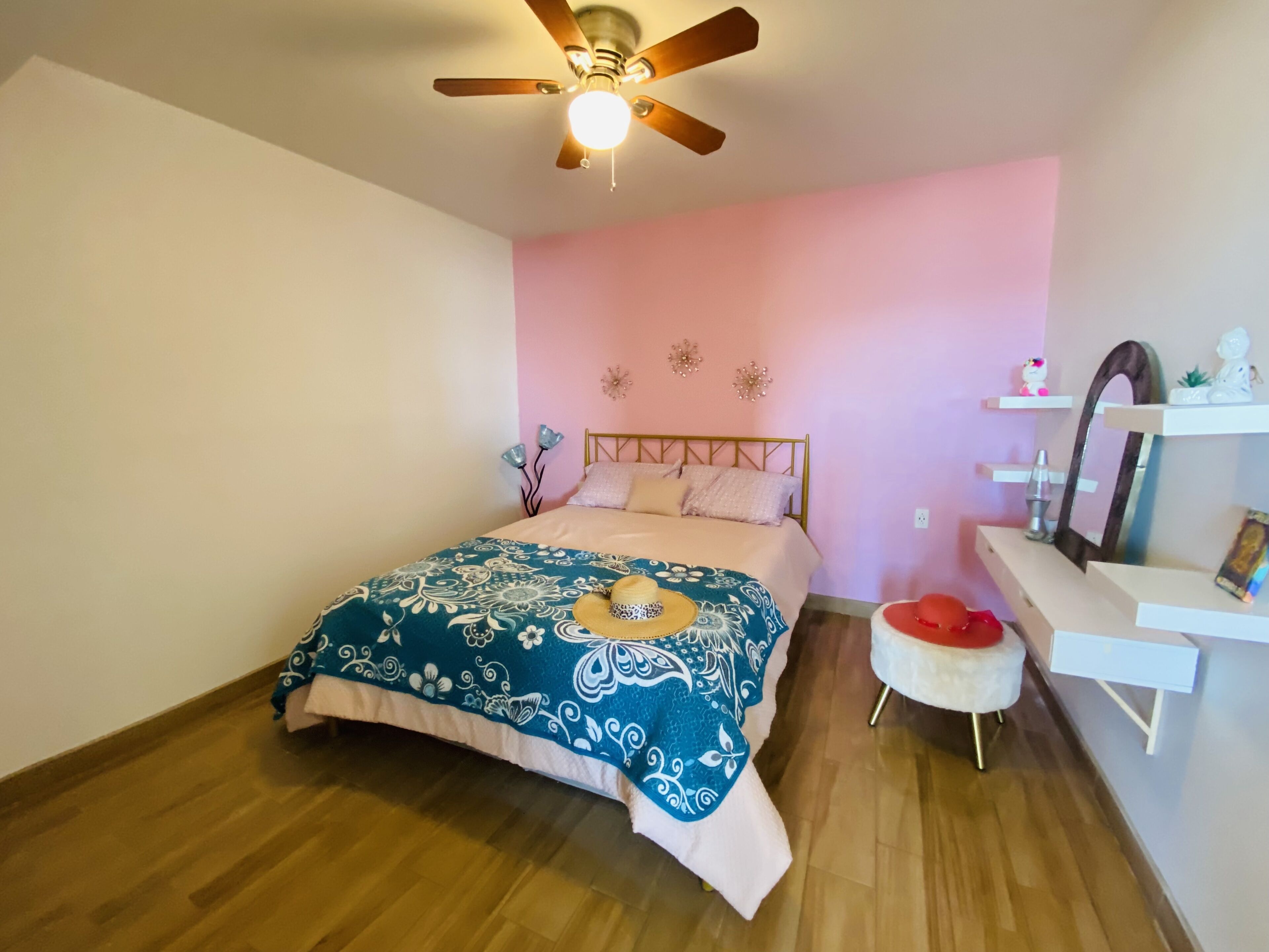 A bedroom with a bed, a ceiling fan, a nightstand, and a dresser.