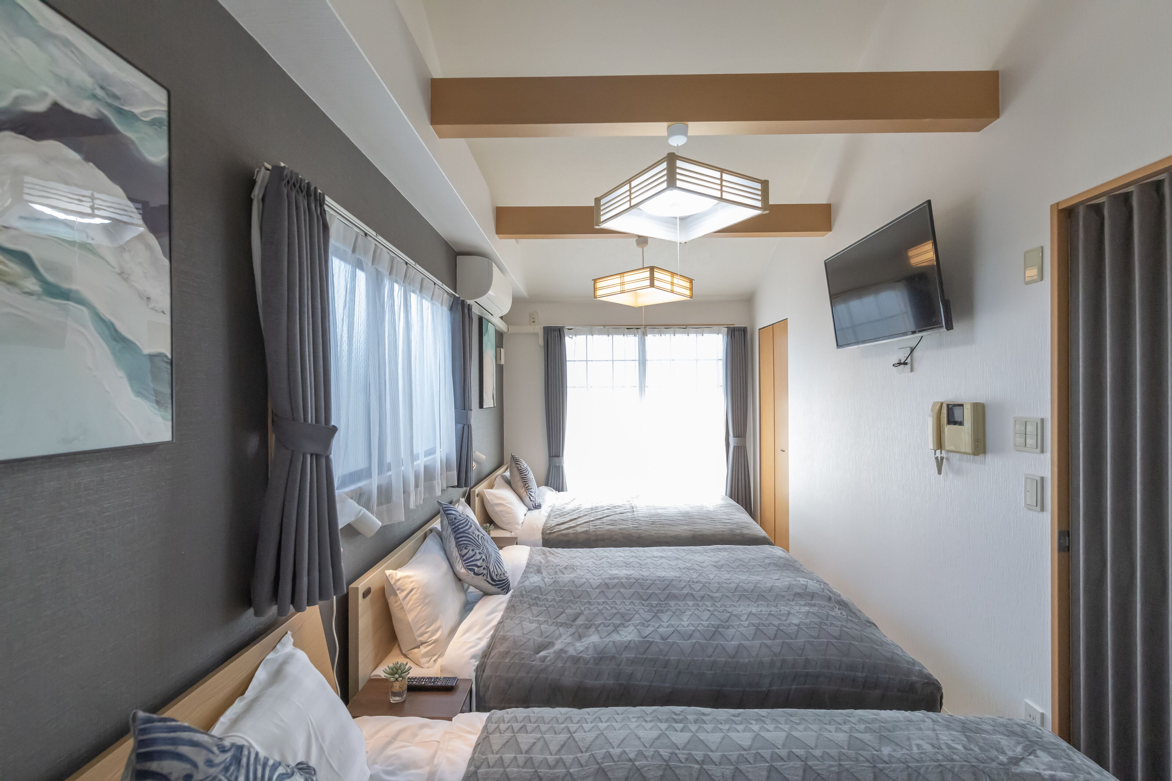 A hotel room with two beds, a TV, and a large window.