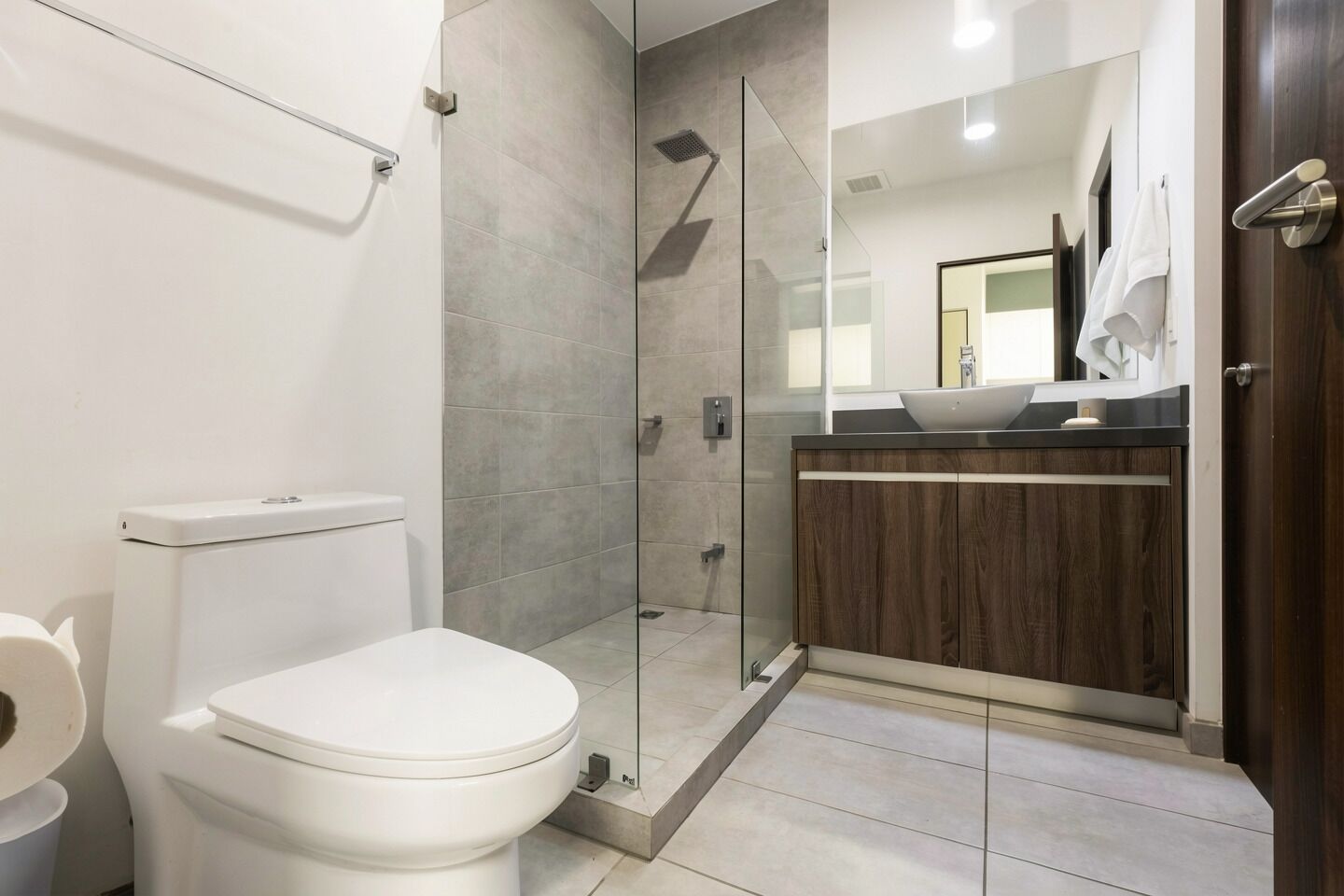 Een moderne badkamer met toilet, douche en wastafel.