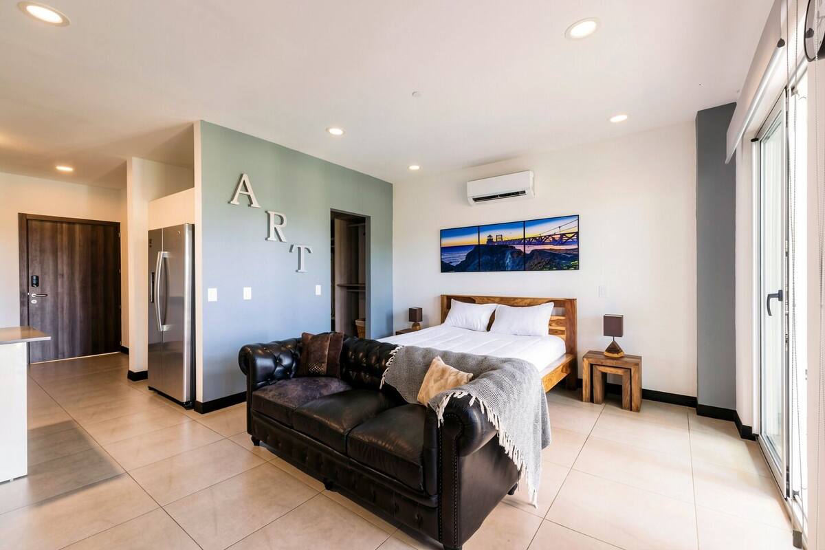 Un dormitorio moderno con una cama grande, un sofá de cuero y un comedor.