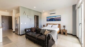 A modern bedroom with a bed, a leather sofa, and a painting on the wall. - Corporate stays Urban flats (Pozos)