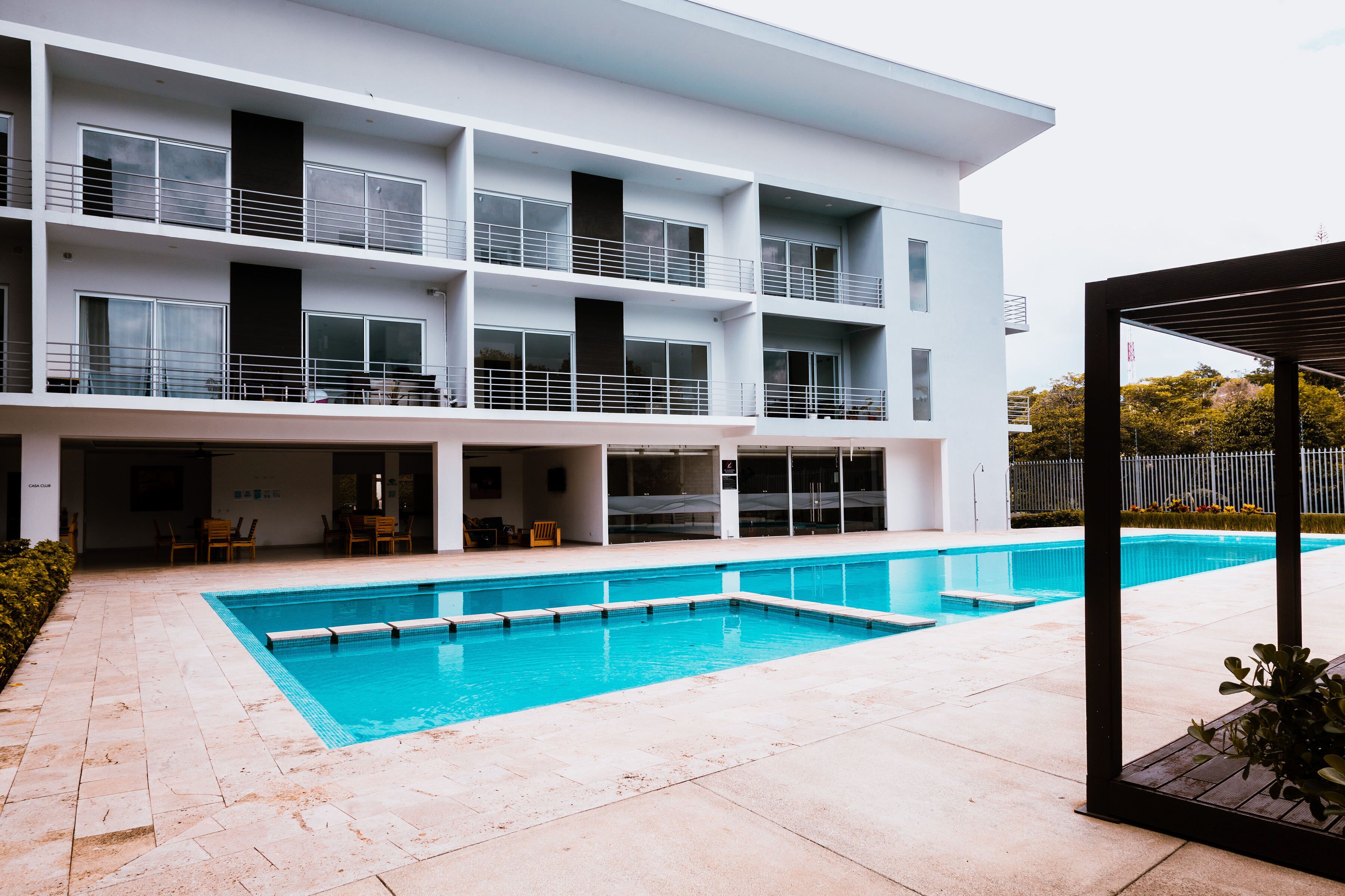 A modern multi-story building with a swimming pool in the foreground.