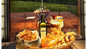 Ein Essbereich im Freien mit einem Ziegelbogen, einem Tisch mit weißem Sonnenschirm und Körben voller Brot und Pasta.