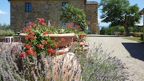 A stone building with a tiled roof, surrounded by gravel and lavender plants.