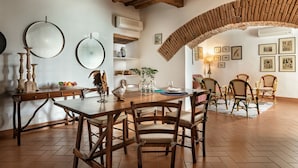 A dining area with a rustic wooden table and chairs, a large mirror, and a decorative bird sculpture.
