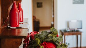 Une table en bois, avec des bouteilles rouges et un bouquet de fleurs rouges.