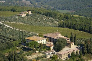 Un domaine rural comprenant plusieurs bâtiments, notamment une maison principale avec un toit en tuiles, une construction plus petite avec un toit plat et une tour en pierre.