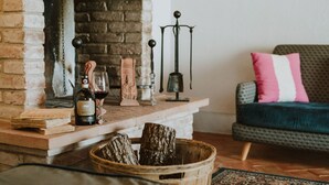 Ein gemütliches Wohnzimmer mit Kamin, einer Couch, einem Couchtisch und einem Holzkorb.