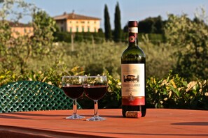 Une bouteille de vin Chianti Classico et deux verres sur une table à l’extérieur.