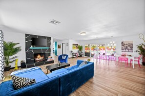 Una sala de estar moderna con chimenea, sofá azul y sillones rosados.