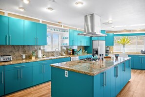 Una cocina moderna con gabinetes color turquesa, encimeras de granito y electrodomésticos de acero inoxidable.