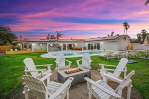 Un patio trasero con una chimenea, mobiliario exterior y una piscina.