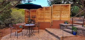 Un espace patio avec une table ronde et des chaises, une clôture en bois et des plantes en pot.