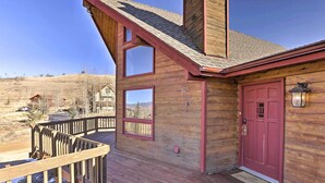 A wooden cabin with a red door, a deck, and a view of a hilly landscape. - 1 Mi to Granby Ranch: Family-Friendly Cabin! (Granby)
