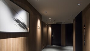 Un pasillo moderno con paneles de madera, una obra enmarcada a la izquierda y suelo alfombrado.