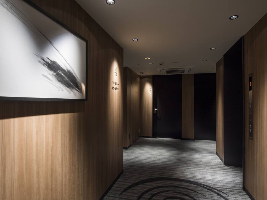 Un pasillo moderno con paneles de madera, una obra enmarcada a la izquierda y suelo alfombrado.