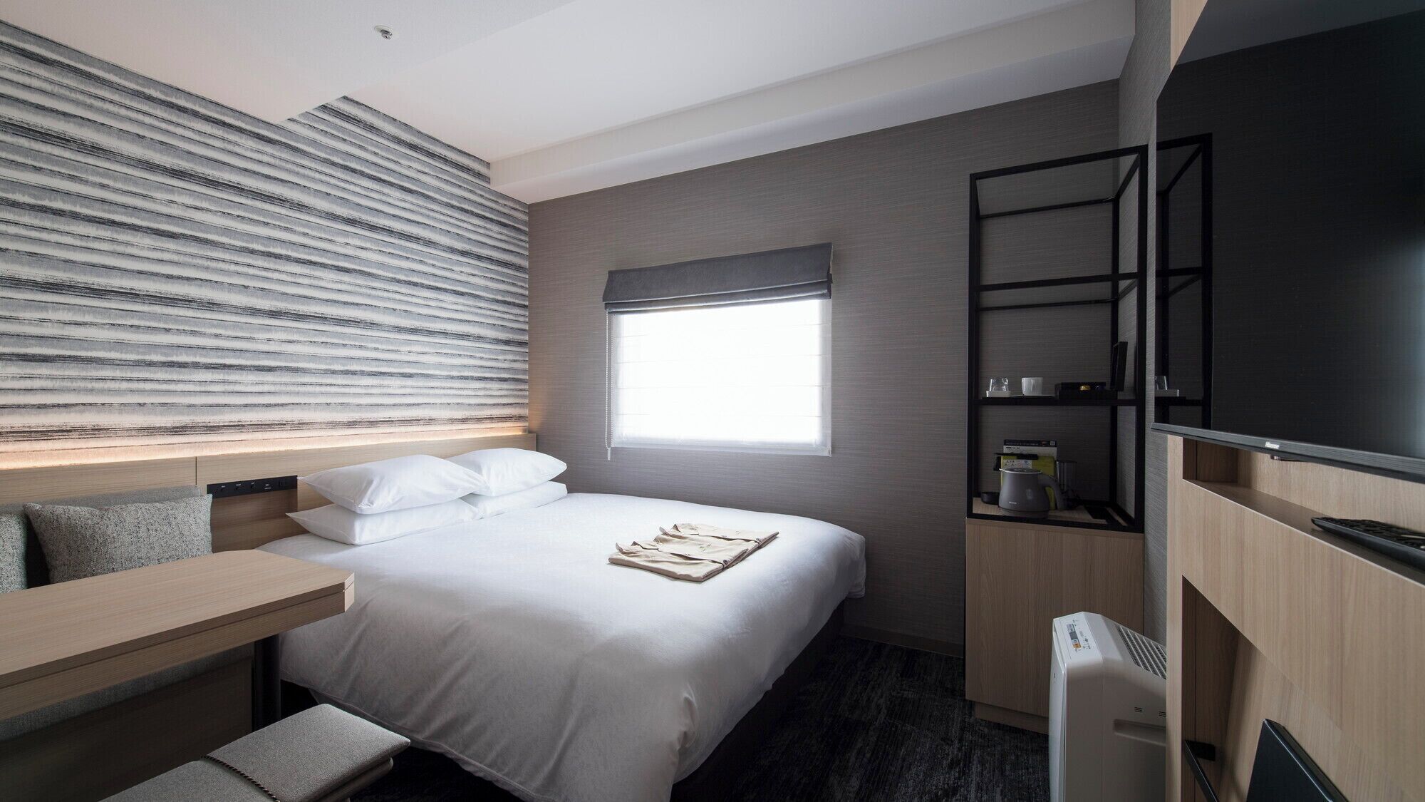 Une chambre d’hôtel avec un lit, un bureau, une télévision et une fenêtre.