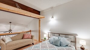 Une chambre à coucher comprenant un lit, un canapé, un ventilateur de plafond et une table de chevet avec une lampe.