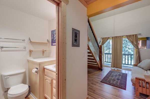 A bathroom with a toilet, sink, and towel rack. A staircase leads to a balcony with a view of trees. - 18SLL - Newly Remodeled - Sleeps 4 (Deming)