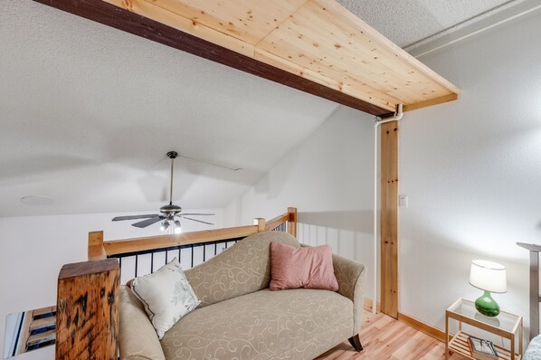 A cozy loft bedroom with a wooden ceiling, a ceiling fan, a wooden bed frame, and a small bedside table with a lamp. - 18SLL - Newly Remodeled - Sleeps 4 (Deming)
