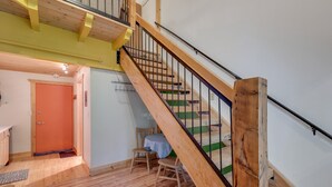 Un escalier en bois avec une rampe métallique menant à un deuxième étage.