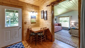 L’intérieur d’un chalet en bois comprend un coin repas, un lit et offre une vue sur l’extérieur.