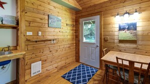 L’intérieur d’un chalet en bois comprend un coin cuisine, une table à manger et une porte avec une fenêtre.