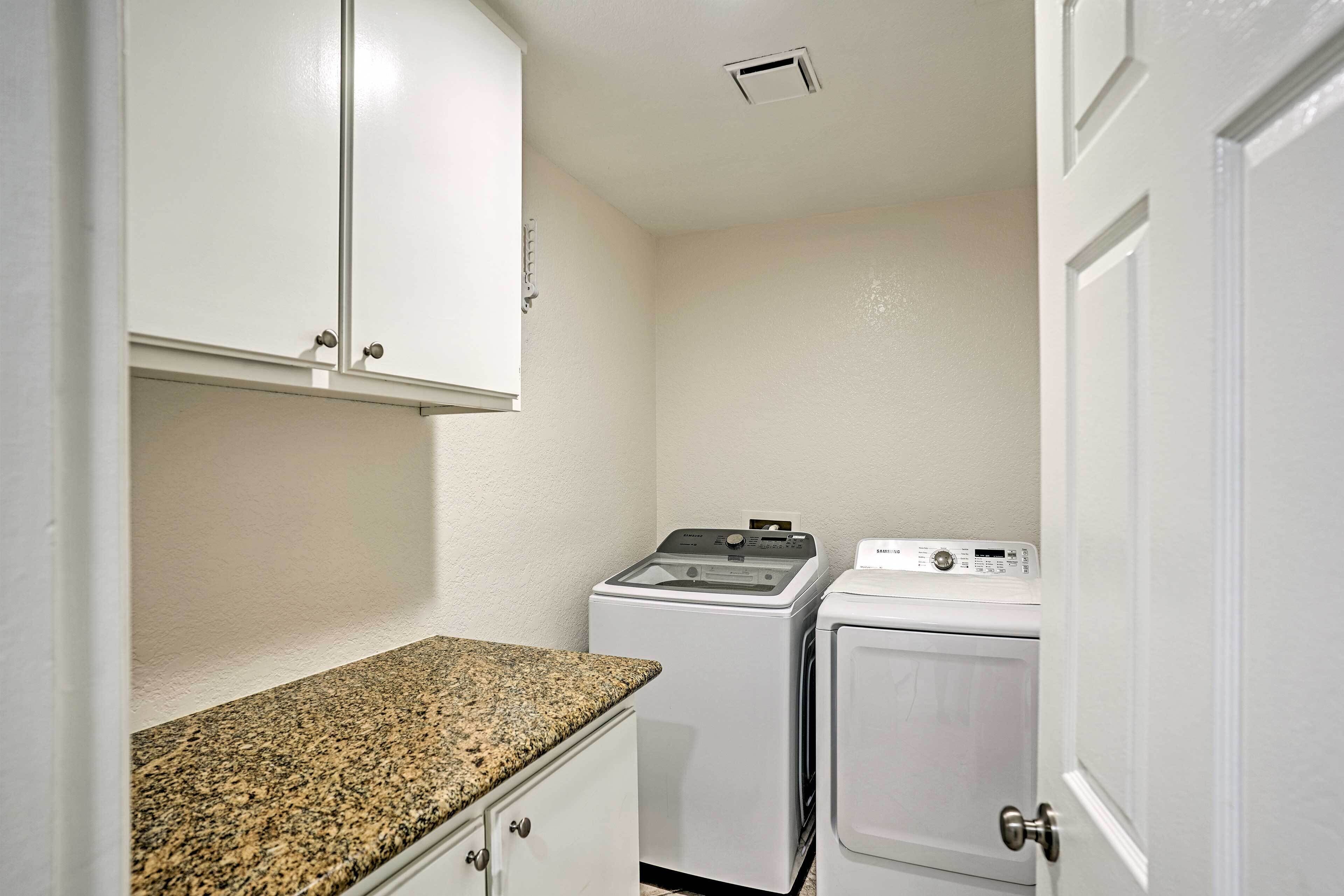 A laundry room with a washing machine, dryer, and cabinets.