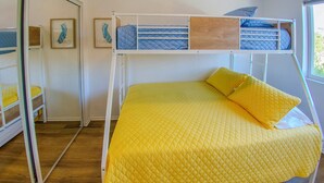 Una cama individual con un colchón y almohadas acolchadas amarillas, un cabecero de madera y una ventana con luz diurna.
