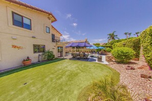 A two-story house with a swimming pool, outdoor seating, and a well-maintained lawn.
