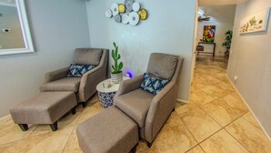 Una habitación con dos sillones, una mesita con un cactus y una pared adornada con platos decorativos.