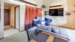 Una sala de estar moderna con un sofá, una mesa de comedor y un televisor montado en la pared.