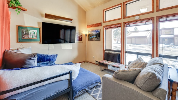 Una habitación con cama, sofá, televisión montada en la pared y ventanas amplias.