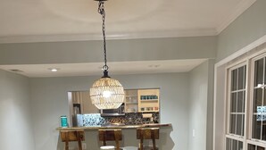 Un espace repas avec une table en bois, des bancs et un luminaire suspendu.