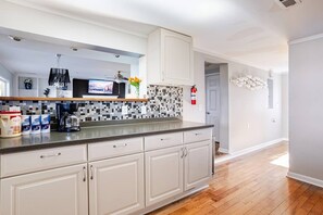 Een keuken met witte kasten, een betegelde spatwand en een houten vloer.