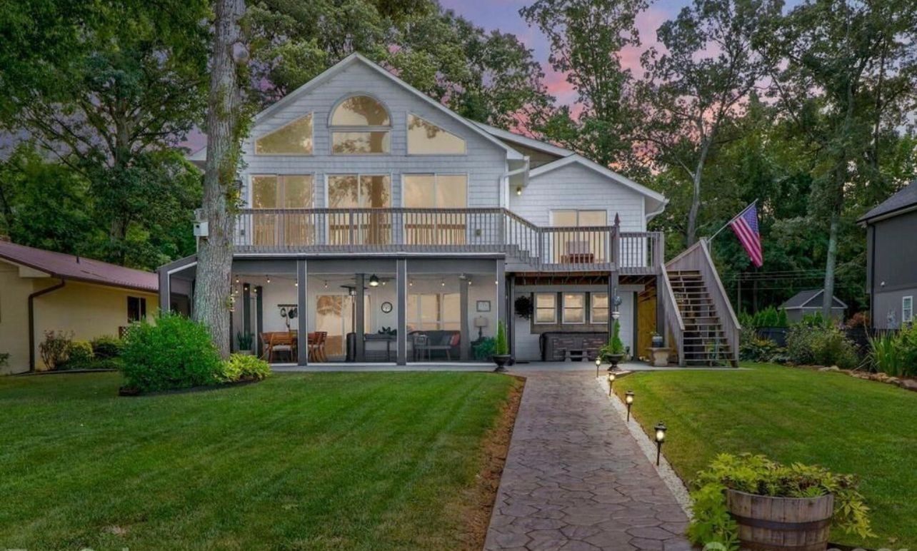 A two-story house with a balcony, a covered patio, and a flag.