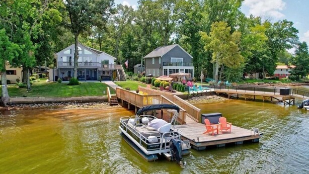 Une péniche était amarrée à un quai en bois, avec une chaise longue et un petit bateau à proximité.