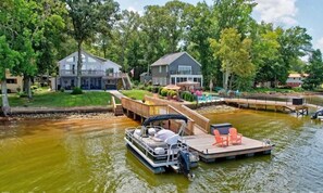 Une péniche était amarrée à un quai en bois, avec une chaise longue et un petit bateau à proximité.