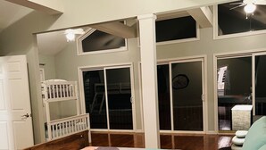 Une chambre avec un grand lit, un bureau et une fenêtre donnant sur un balcon.