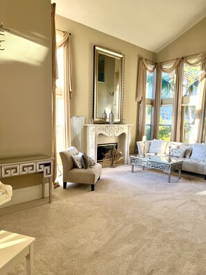 A spacious living room with a fireplace, a sofa, a coffee table, and a decorative mirror.