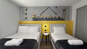 A double bed room with two beds, a small table, and a wall with a Minion-themed mural. - 3 King Masters + Private Pool | 15 Min Disney (Kissimmee)