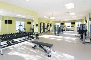 A gym with exercise equipment, a bench, and a mirror.